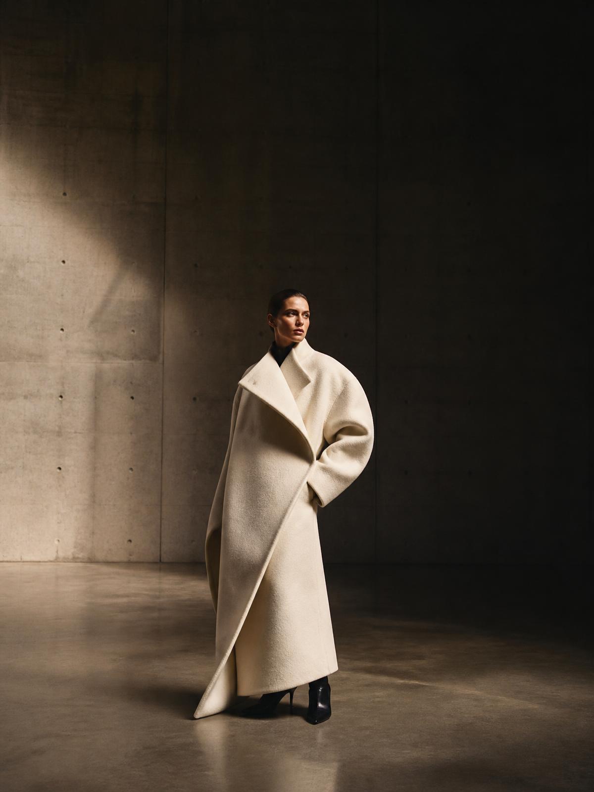 Model wearing the Atelier oversized wool coat in a concrete gallery